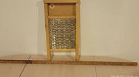 Small wooden washboard with metal scrubbing surface propped upright behind long wooden yard stick.
