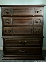 Front view of the wooden tall boy dresser showing all five drawers and brass handles and knobs.