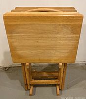 Four wooden folding TV tables stacked together, showing front view with one cracked edge visible.