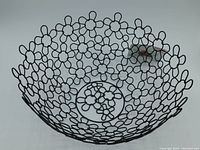 Top and side views of the black flower-shaped open design bowl showing details of interlocking flower patterns in powder coated steel.