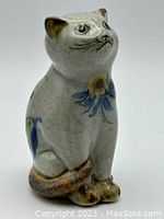 Side view of the gray tonal pottery cat showing the detailed painted floral decoration on chest and feet area.