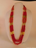 Front view of multi-strand bohemian style seed bead necklace in red coral and bronze tones on display bust.
