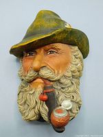 Front angled view showing face details, pipe, beard, and alpine hat with flower.