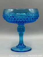 Front view of vintage blue glass pedestal bowl showing diamond pattern accents on the bowl and sculpted stem on the pedestal.