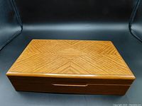 Top view of the closed wood jewelry box showing the diamond diagonal inlaid geometric pattern on light mid-brown wood surface.