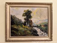 Full view of the framed oil painting showing landscape scene with river, trees, and sky.