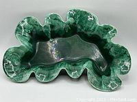 Top angled view of green glazed scalloped ceramic bowl showing interior shape and glossy finish.