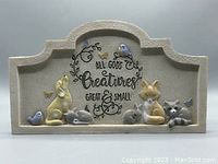 Full front view of the beige textured wall plaque with raised animal figures and inscription.