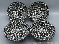 Four black and white ceramic bowls with dense skull print pattern inside and outside, arranged in pairs.