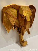 Full view of gold geometric elephant head wall decor mounted on white wall, showing detailed surface patterns and gold finish.