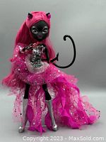 Full body image showing black skinned doll with bright pink hair, pink sequined dress and silver boots.