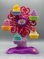 Full view of the colorful My Little Pony Ponyville Ferris Wheel toy standing on a purple base with six cupcake buckets in multiple colors attached to the wheel.