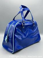 Royal blue plastic bag with two handles, baby blue zipper and trim, shown from front angled side.
