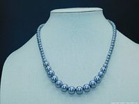 Full view of silver-gray graduated pearl necklace displayed on a white bust showing strand length and pearl size variation.