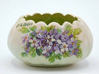Close-up photo of the vase showing hand-painted white and purple flowers with green leaves on a pastel pink to green scalloped edged pottery bowl. The word 'Eildon' is hand-painted above the flowers.