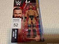 Front view of WWE Drew McIntyre action figure in sealed packaging, showing figure and card with wrestler's image and branding.