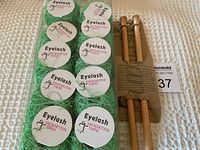 Top view of ten skeins of green eyelash yarn stacked in two columns next to packaged U.S. size 15 wooden knitting needles.