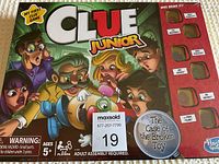 Front box photo of Clue Junior board game The Case of the Broken Toy with cartoon children and broken toy dog illustration.