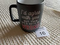 Photo of black ceramic coffee mug showing one side of humorous saying printed in white and red text.