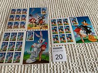 Four sheets of self-adhesive stamps featuring Looney Tunes characters laid out on carpet.