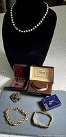 Photo of all seven jewelry pieces displayed: two necklaces, three bracelets, one anklet, and one brooch, with boxes visible for some items.