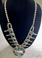 Full front view of necklace on display bust showing bead chain, blossom pendants, naja pendant