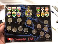 Full view of the 1992 Canadian 125th Anniversary Coin Set with all 12 coins displayed with corresponding provincial and territorial shields on black map background.