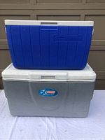 Two large Coleman coolers stacked, gray cooler on the bottom with Xtreme logo, blue cooler on top.