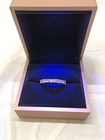 Photo showing front view of the ladies ring with clear stones set in a blue velvet ring box.