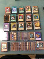 Top view of multiple stacks of Yu-Gi-Oh! cards arranged on a surface showing a variety of card types and designs.