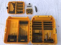 Top-down view of four yellow DEWALT plastic cases containing assorted drill bits and screwdriver bits of various sizes and types on a white surface.