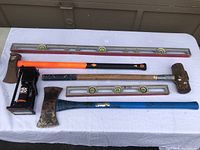 Full layout of all tools including sledgehammer, axe, two levels, and bottle jack press on a white cloth surface.