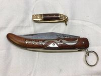 Two folding pocket knives laid side by side showing closed blades and decorative handles