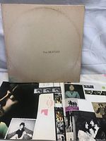 The Beatles 'White Album' cover with plain white front and visible aging spots, inner artwork visible with band member photos and collage-style images.