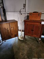 Closed view of the bar cabinet, wooden case box on top of small cabinet, and floor lamp standing between them