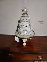 Full view of the assembled incense burner with its tiered perforated metal sections and beast-shaped legs standing on a wooden surface.
