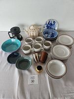 Top view showing full lot arrangement: Julen Christmas plates, Colonial Stoneware sets, teapot, French press, German cups