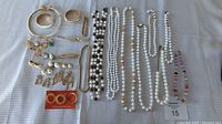 Full lot laid out on white cloth showing all necklaces, earrings, and bracelets including close-ups of bead detail and metal items.