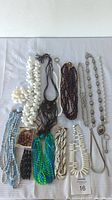 Overhead photo of assorted costume jewelry laid out including various beaded necklaces, bracelets, and a boxed small bead set.