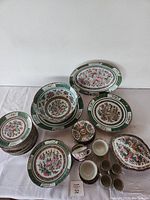 Full assortment of plates, cups, bowls, platters, and covered dish laid out on table