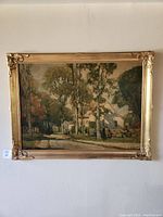 Front view of the framed artwork showing a scenic outdoor street view with three figures and an ornate gold-tone frame.