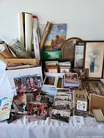 Wide view of assorted vintage postcards, travel books, rolls of maps or posters, card sets, and picture frames.
