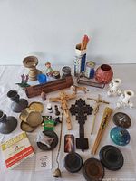 Overview of entire lot showing assorted incense holders, religious items, crucifixes, candles, matches, and decorative pieces arranged on a white table.