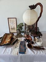 Overview of main grouping on table showing lantern, Buddha, textiles, figurines, bonsai and ceramic swan