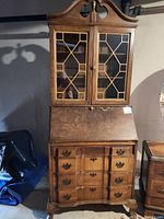 Full view of Morris secretary desk showing wooden construction, slant-front desk, four lower drawers, and two-door glass display cabinet on top.