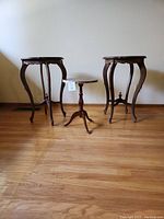 Photo of the three wooden tables side by side, two tall round tables and one small oval table in the center.