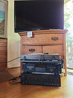 Insignia 38-inch TV on top of wooden dresser; below the dresser are audio components including turntable, cassette deck, and receiver.