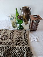 Full lot on display including pottery vase, three glass vases, stained glass lantern, and woven textile.