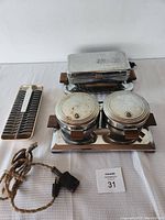 Overview of the vintage waffle maker, cornbread maker, and metal ice tray displayed on a white surface