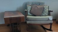 View of vintage upholstered rocking chair next to wooden side table